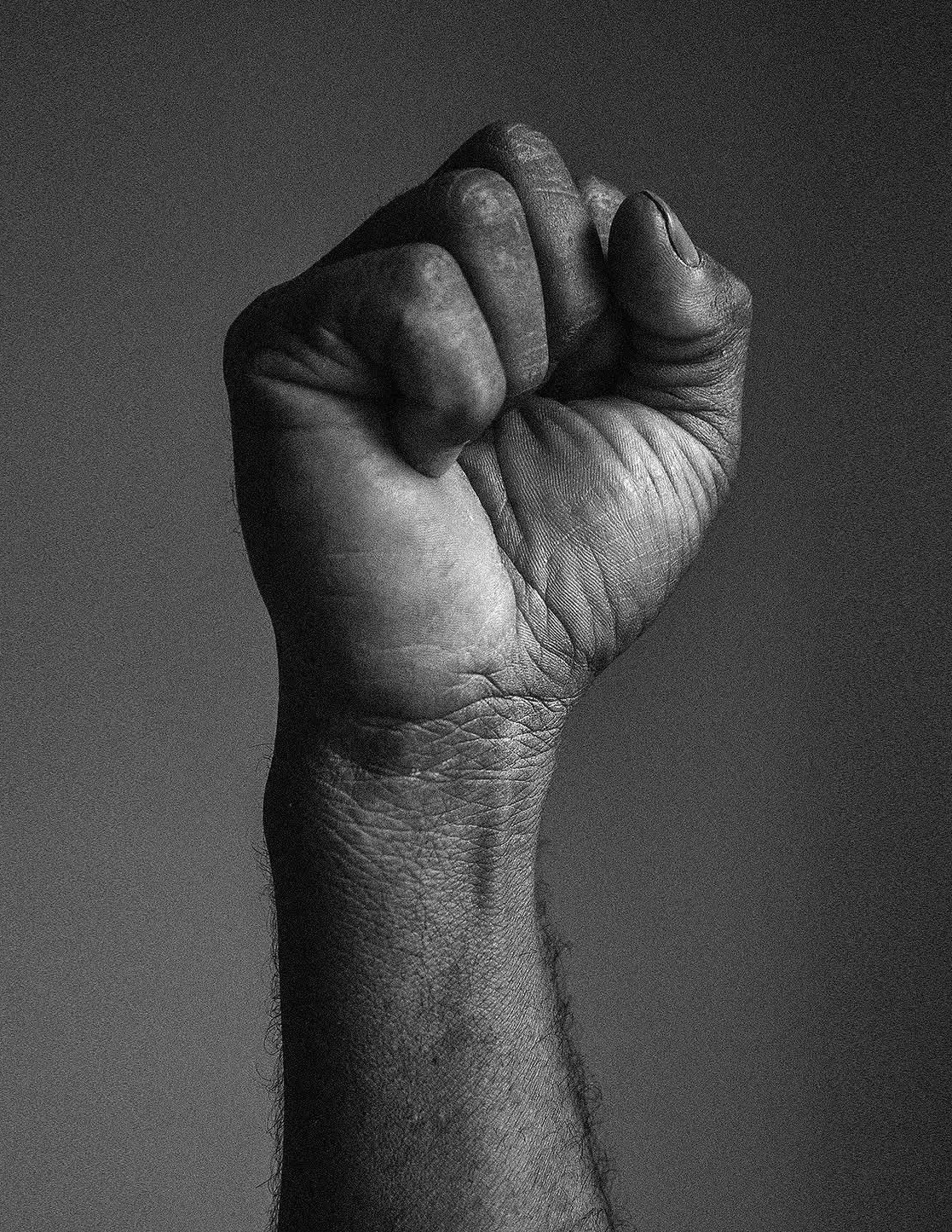 Black and white photograph of a tightly closed fist raised against a neutral background