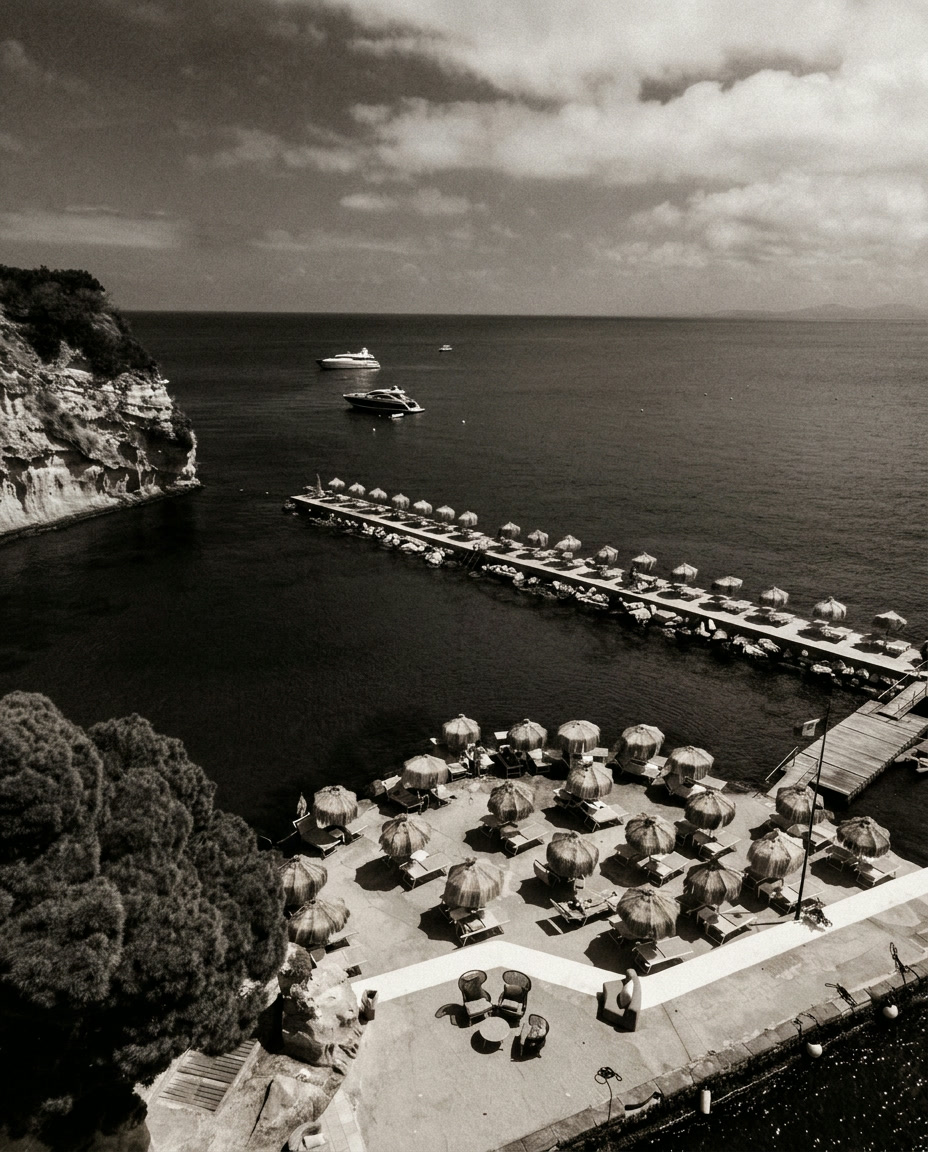 Black and white aerial photograph of a sun terrace and stone pier extending into the sea, Ischia